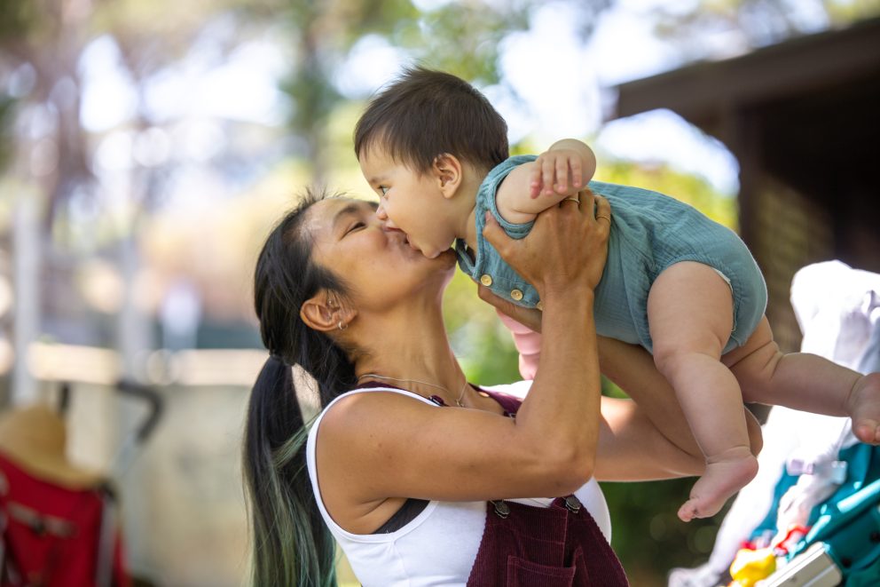 Mother holding baby and kissing him on his cheek.