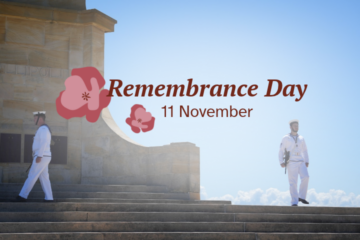 Two sailors in white uniforms stand guard at a stone memorial on Remembrance Day, 11 November.