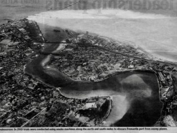 A black-and-white aerial photograph of Fremantle port, showing the coastline, harbor, docks, buildings, and surrounding areas. The caption mentions 1943 smoke machine trials to obscure the port from enemy planes.