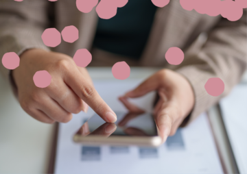 A person uses a smartphone, tapping the screen with one hand while holding the device with the other. Pink circular shapes are scattered across the image, partly obscuring the person and the phone.