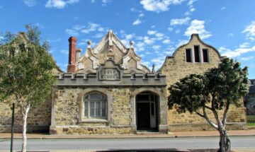 Historic stone building with a decorative gable and a plaque reading Boys School above the entrance.